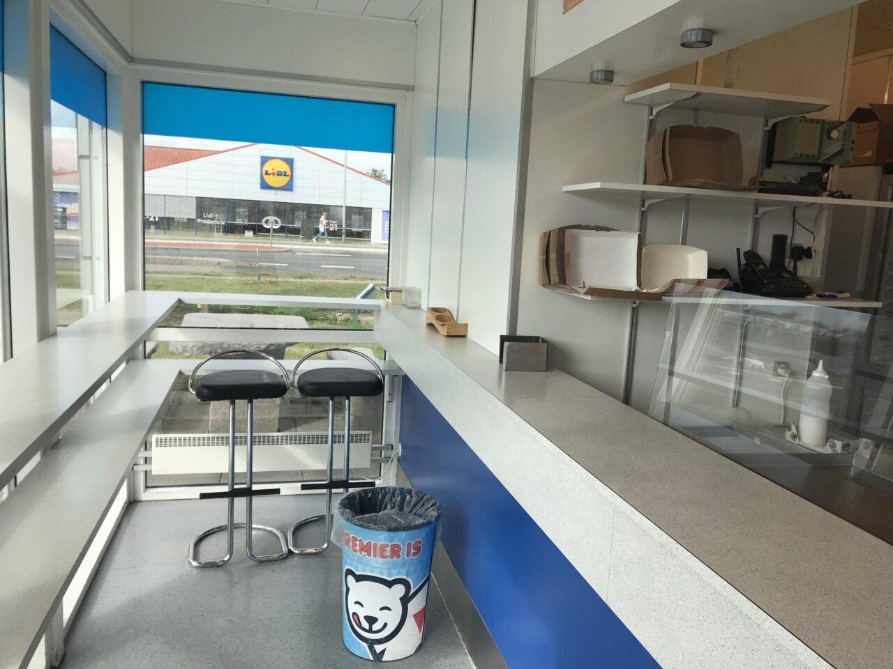 Grillbar til salg i Fredericia - Det er en hvid barbord/disk hvor der under er blå, der er to siddepladser og vinduer