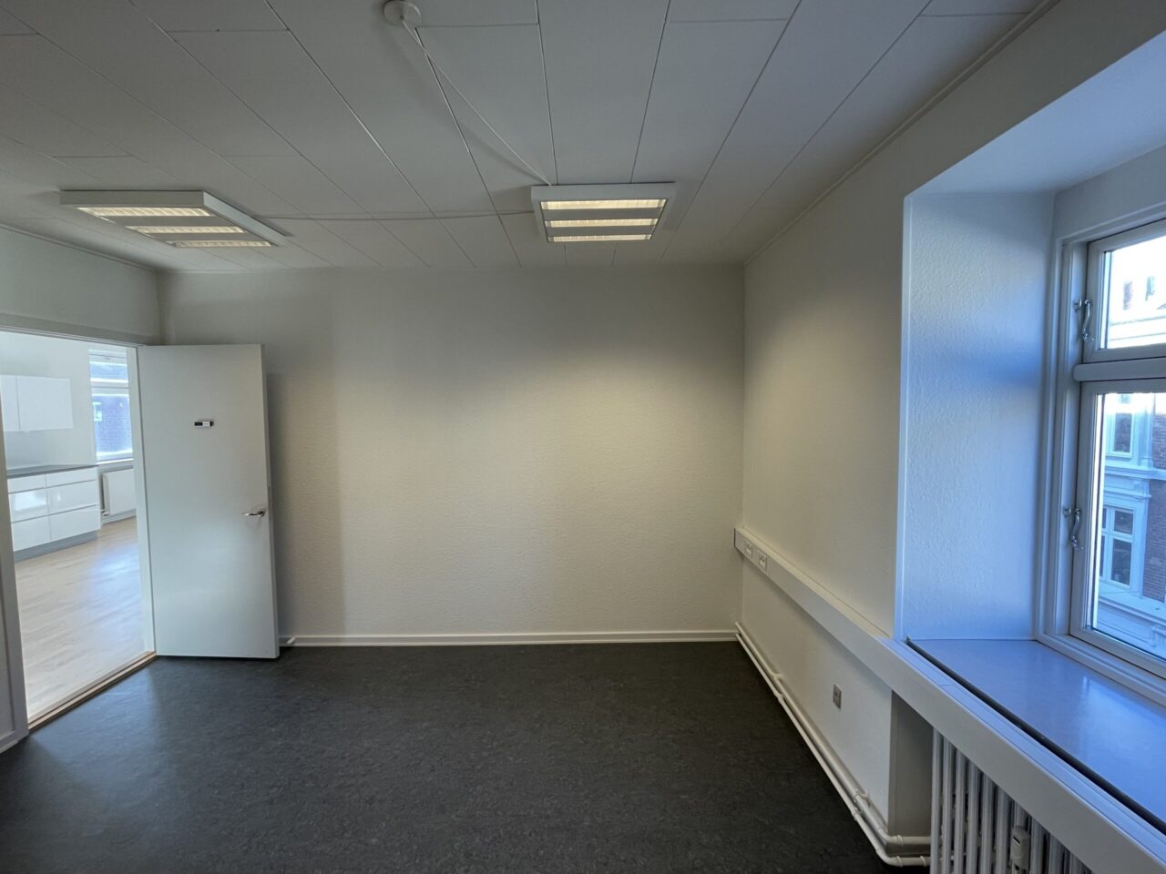 Lokaler til leje i Kolding - Lokale med hvide vægge og sort gulv med et vindue