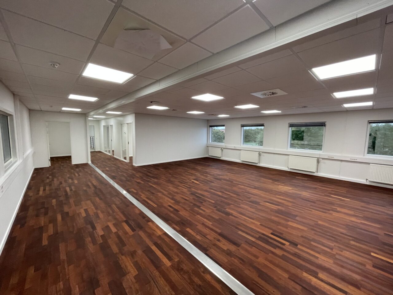 Kontor til leje i Kolding - Hvide vægge og loft med mørkebrun trægulv og vinduer
